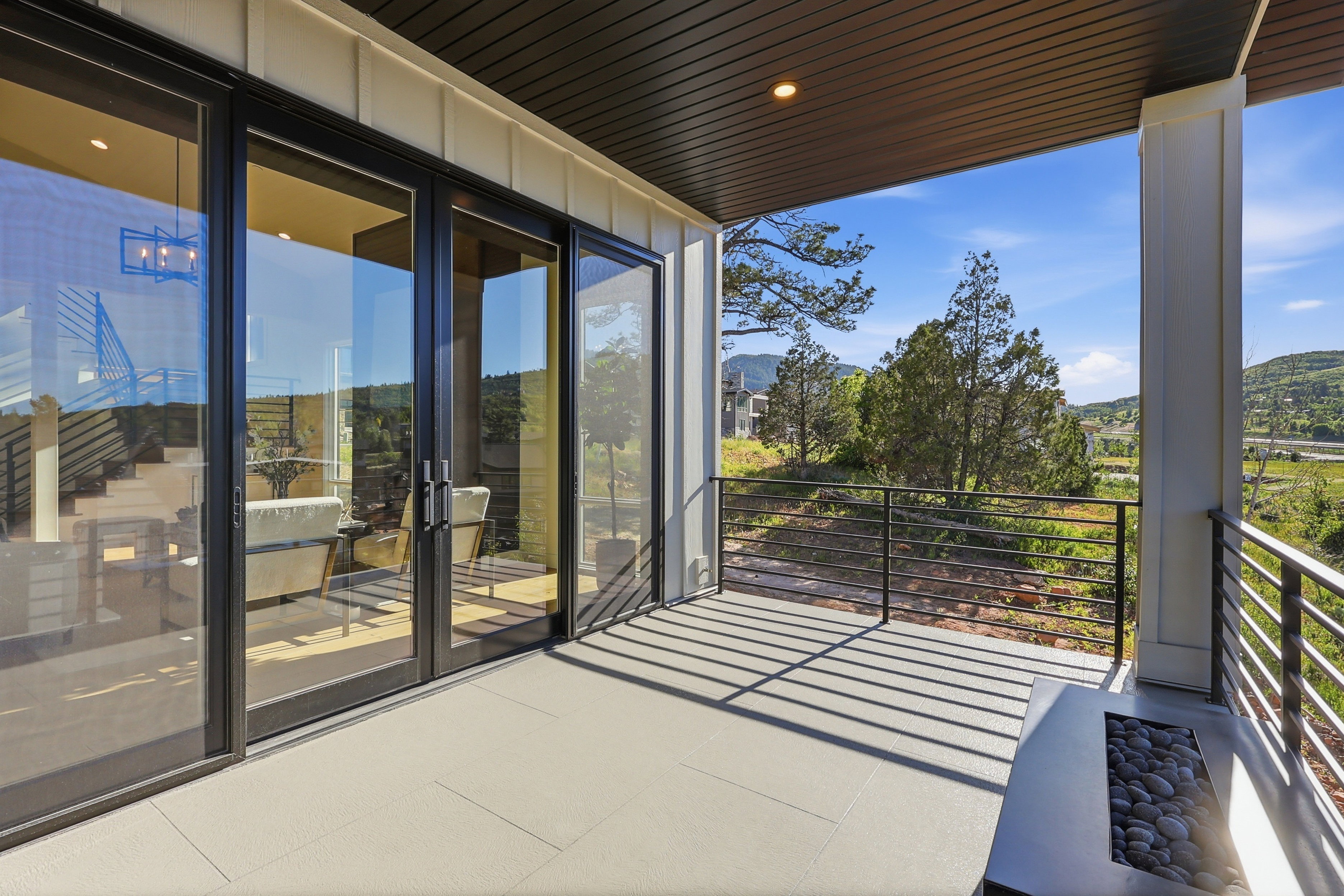 Covered outdoor patio with a plank ceiling, board and batten siding, and a linear rock-filled fire pit