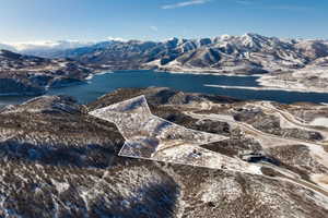 Expansive land parcel outlined against a backdrop of snow-dusted mountains and a substantial body of water