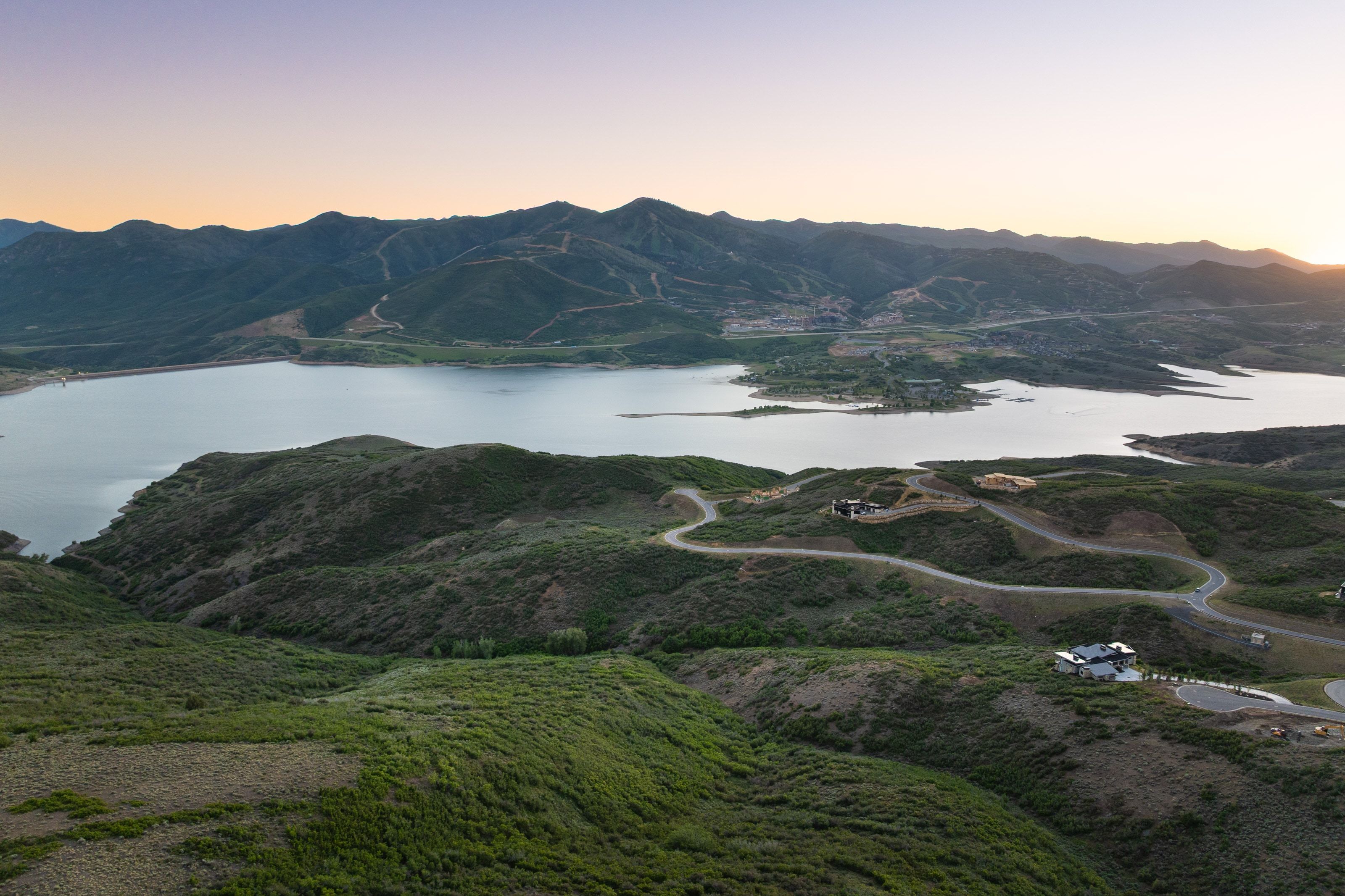 Expansive mountain landscape with a large body of water, rolling hills, and distant mountain ranges