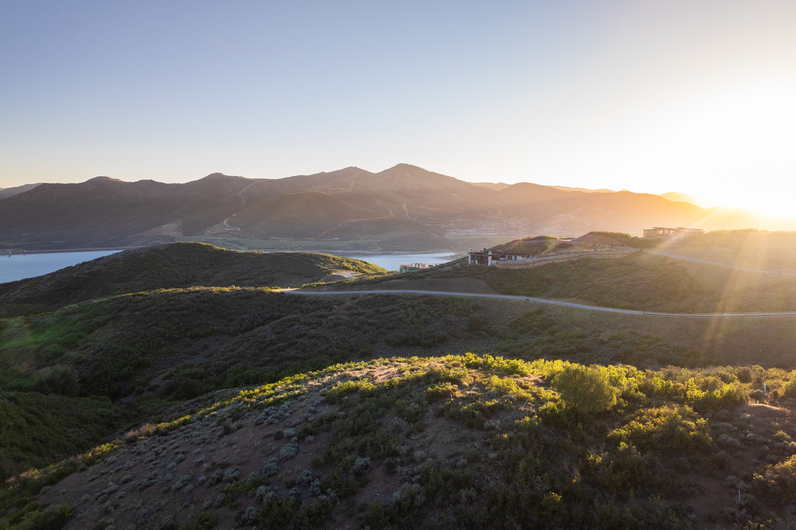 Expansive hillside lot featuring a distant water body, mountain backdrop, and natural landscaping