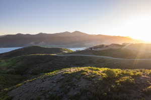Expansive hillside lot featuring a distant water body, mountain backdrop, and natural landscaping