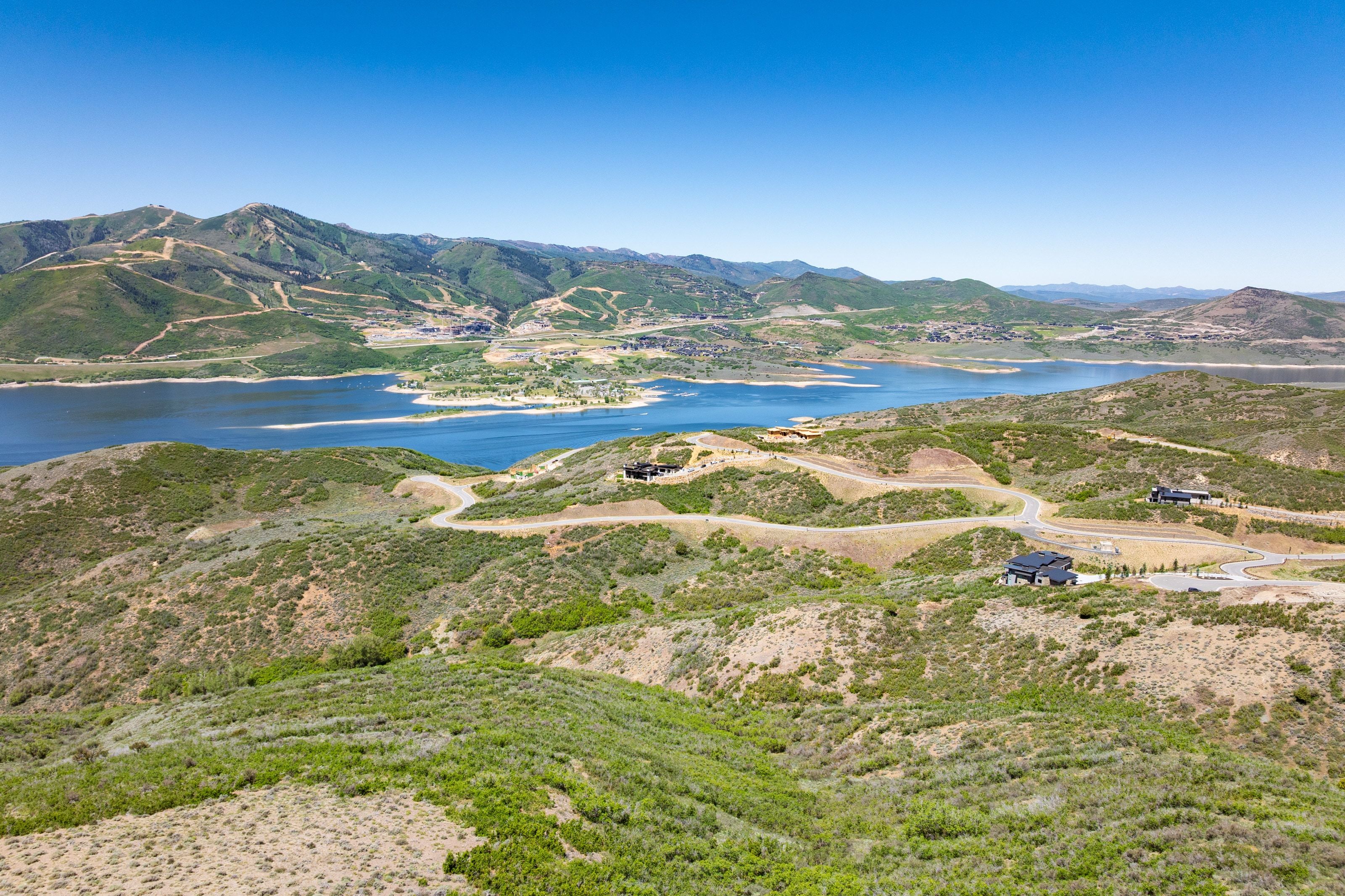 Expansive landscape featuring a large body of water, rolling hills, and distant mountains