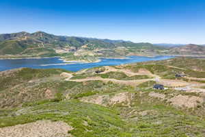 Expansive landscape featuring a large body of water, rolling hills, and distant mountains