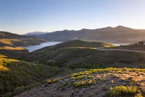Expansive mountainous terrain featuring a large body of water, distant snow-capped peaks, and a property with a dark-toned exterior