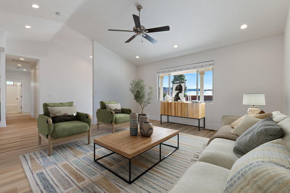 Spacious living area featuring light wood-finish flooring, vaulted ceilings, and recessed lighting