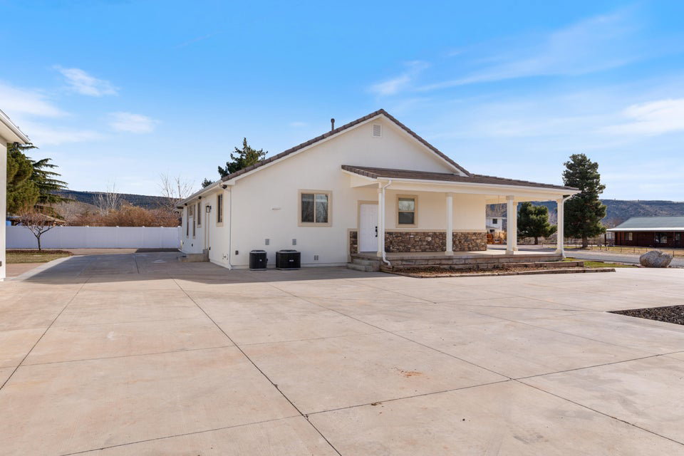 White stucco exterior featuring a covered porch with stone detailing and white columns