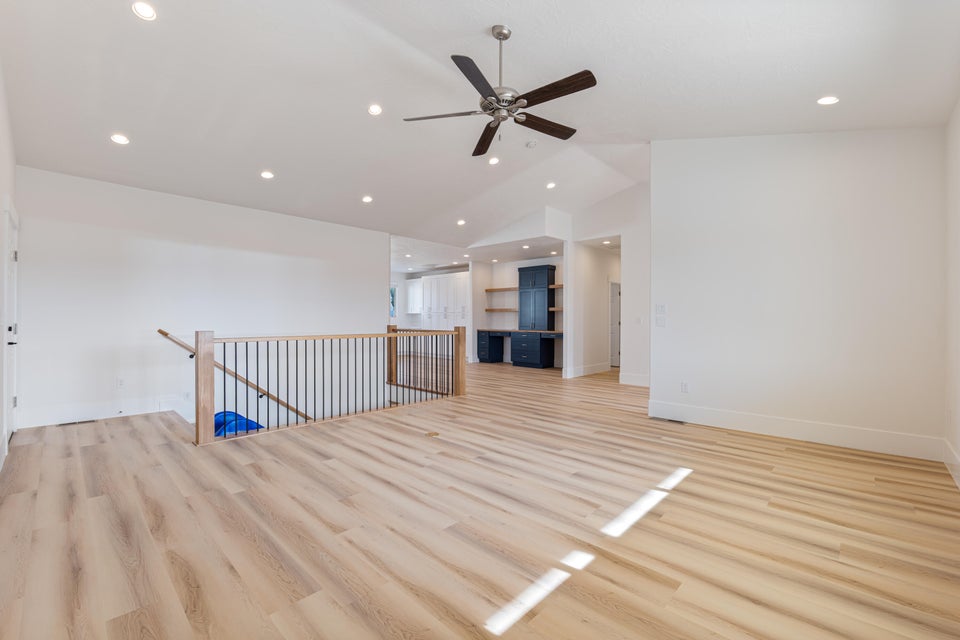 Spacious room featuring wood-finish flooring, recessed lighting, and a ceiling fan