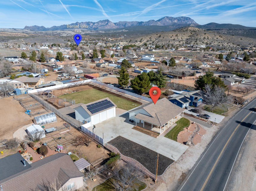 Expansive property featuring a single-story residence with a covered porch, a large detached garage with solar panels, and a fenced cultivation area with multiple greenhouses