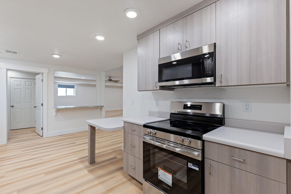 Kitchen featuring stainless steel appliances, light wood-finish flooring, white countertops, and contemporary cabinetry