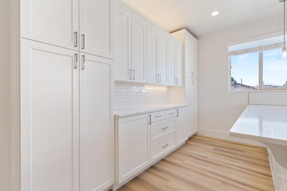 Kitchen featuring extensive white shaker cabinetry with brushed nickel hardware, white subway tile backsplash, white countertops, and wood-finish flooring
