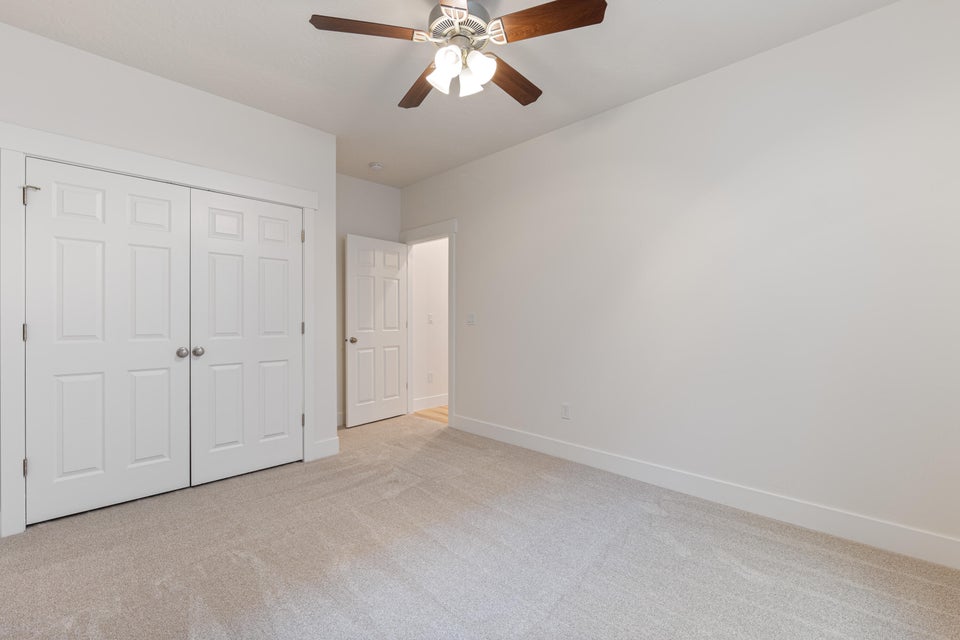 Neutral tone wall paint with a ceiling fan featuring wood-finish blades and integrated lighting