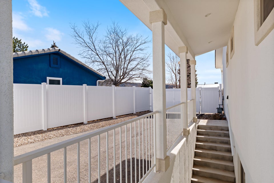 Covered entryway with concrete steps and an adjacent white privacy fence