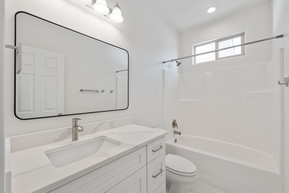 Vanity with an integrated rectangular sink, stone-finish countertop, and brushed nickel faucet