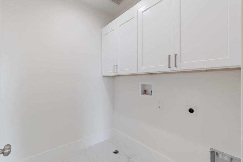 Laundry area featuring white shaker-style cabinetry with brushed nickel hardware, white walls, and a white tiled floor with a central drain