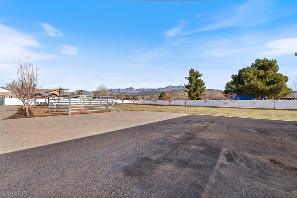 Expansive paved area with metal fencing, bordered by a white privacy wall