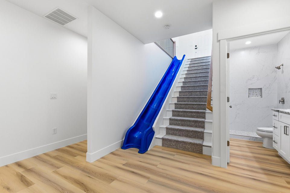 Staircase featuring carpeted treads, a wooden handrail, and a built-in blue slide