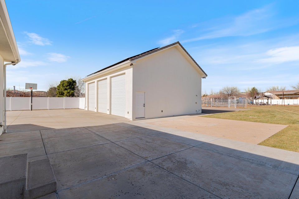 Detached three-car garage with white stucco exterior and dark-shingled roof