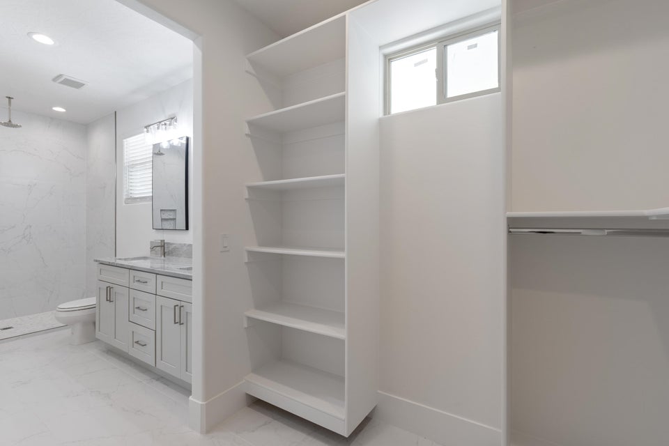Walk-in closet featuring built-in shelving, hanging rod, and a window for natural illumination