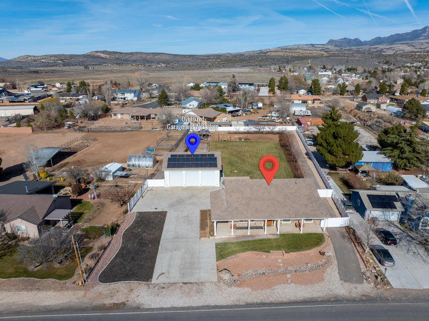 Expansive property featuring a single-story residence with a covered front porch, a multi-car driveway, and an oversized detached garage with rooftop solar panels