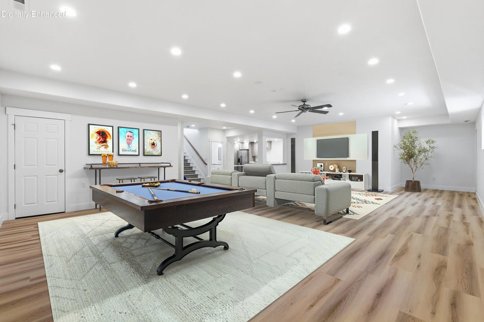 Spacious entertainment area featuring wood-finish flooring, recessed lighting, and a ceiling fan