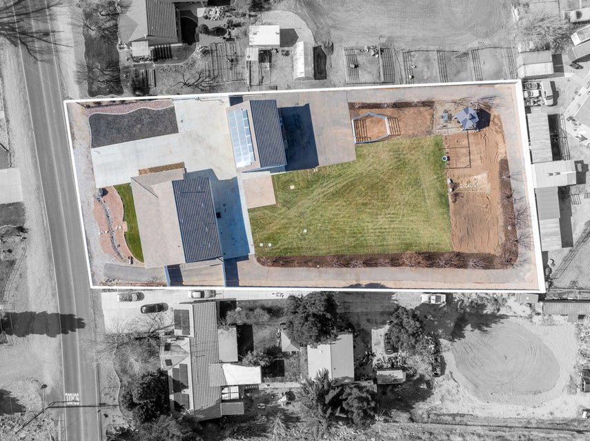 Extensive property featuring a large concrete driveway, substantial grassed areas, and a structured outdoor patio