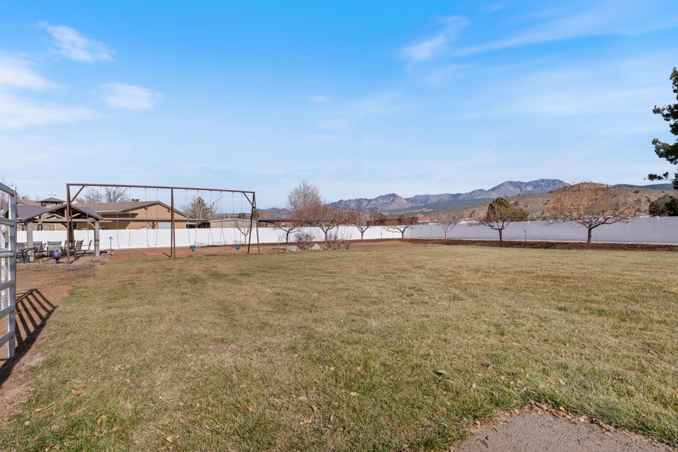 Expansive backyard featuring a large grass area and a white privacy fence