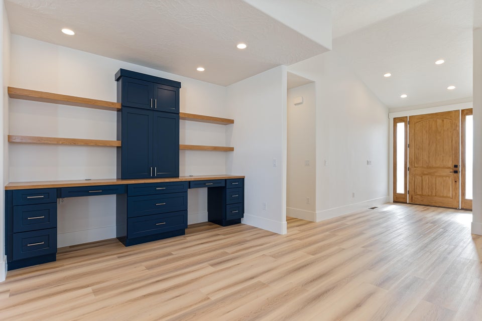 Integrated workspace featuring navy cabinetry, wood-finish countertops, and natural wood floating shelves