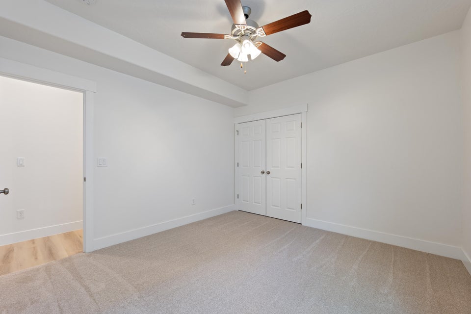 Carpeted room featuring a ceiling fan with integrated lighting, white baseboards, and a double-door closet with paneled doors
