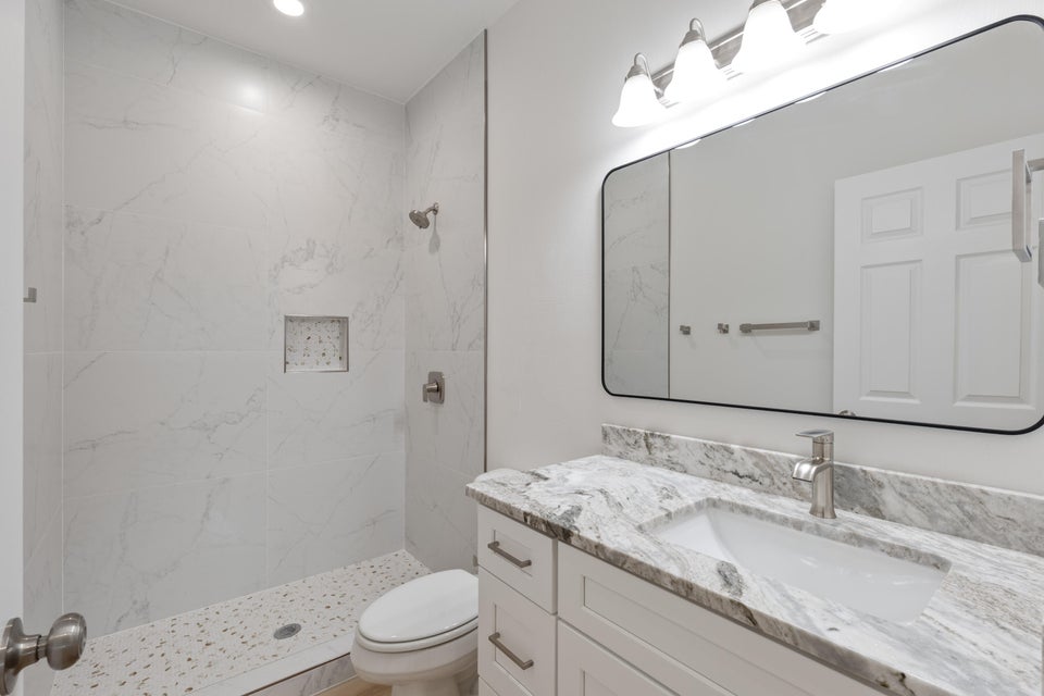 Bathroom featuring a white vanity with a granite-style countertop, undermount sink, and brushed nickel hardware