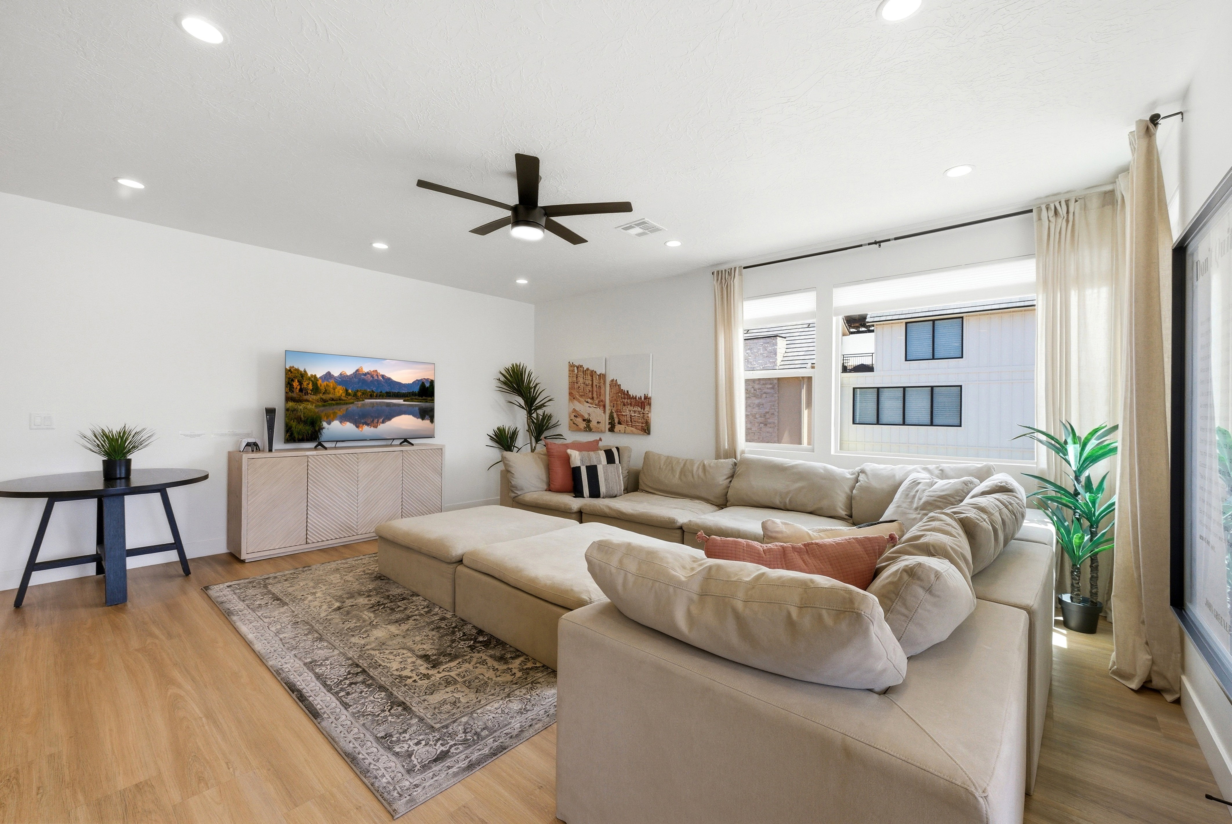 Spacious living area featuring light wood-finish flooring, recessed lighting, and a modern ceiling fan