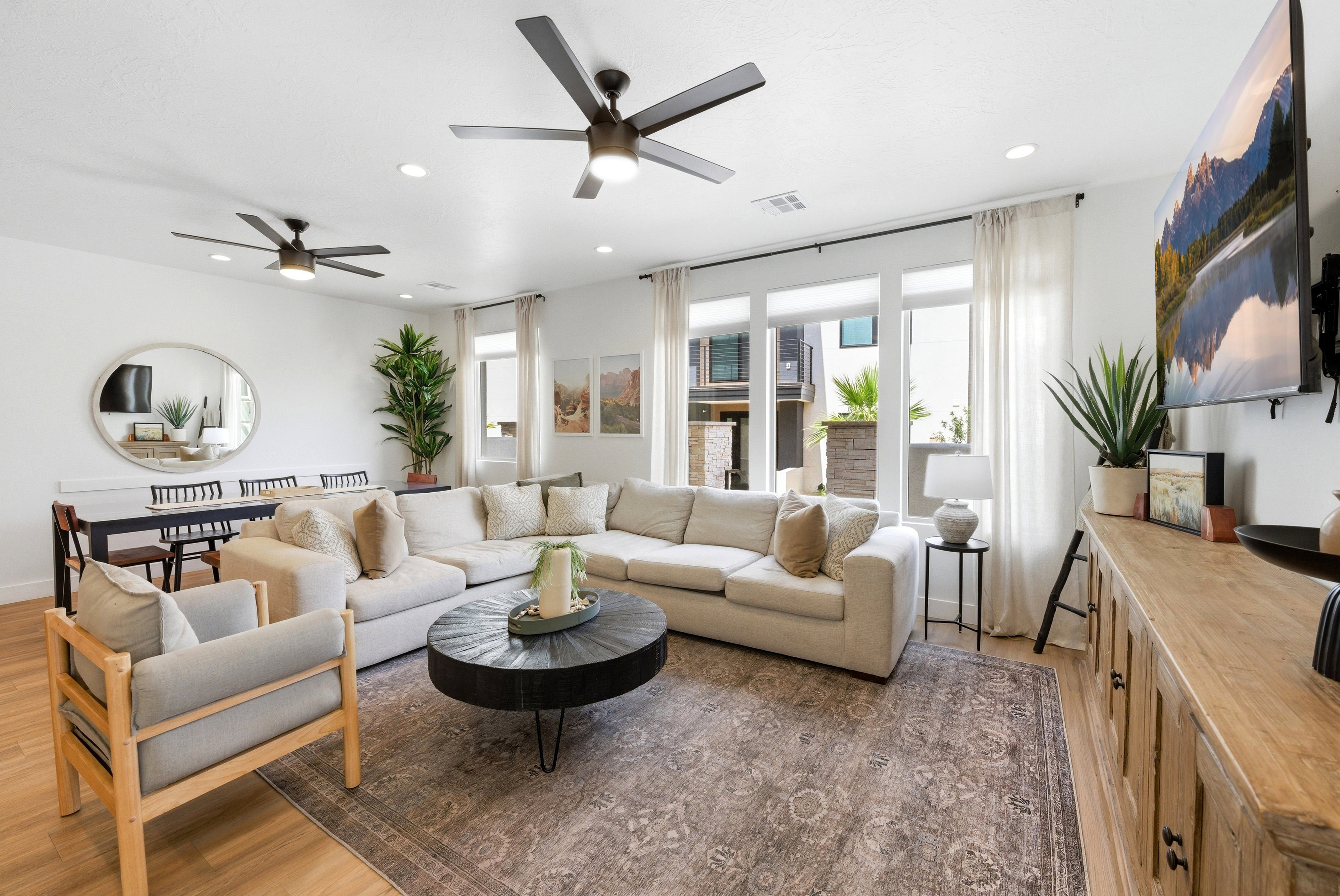 Open-concept living area featuring light wood-finish flooring, recessed lighting, and dual ceiling fans