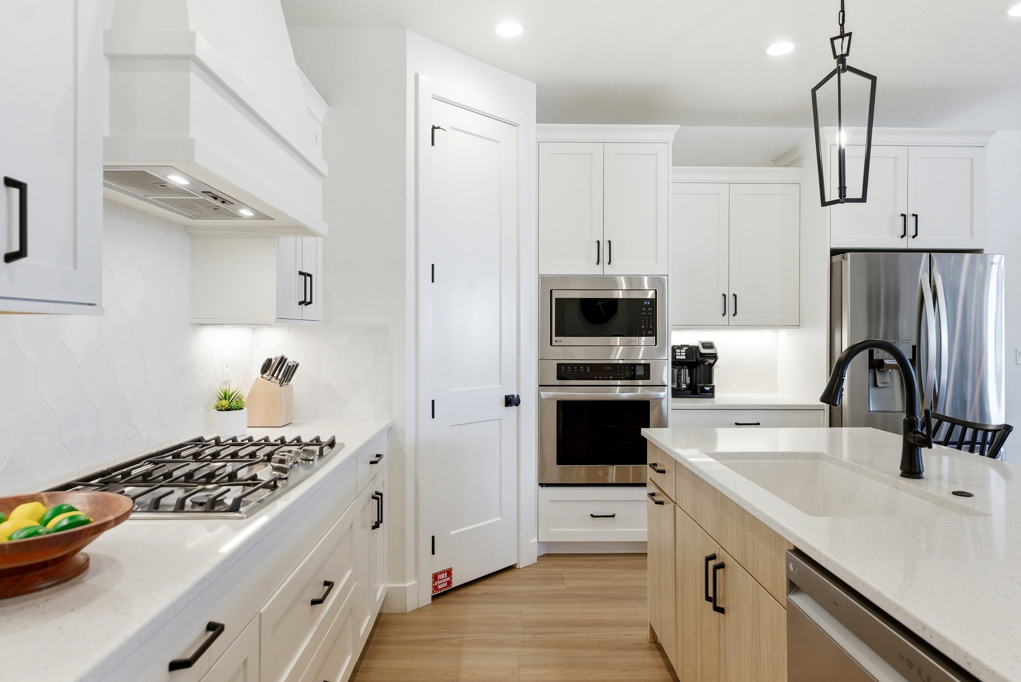 Modern kitchen featuring white cabinetry, light wood-finish flooring, stainless steel appliances, a gas range, and a kitchen island with an undermount sink
