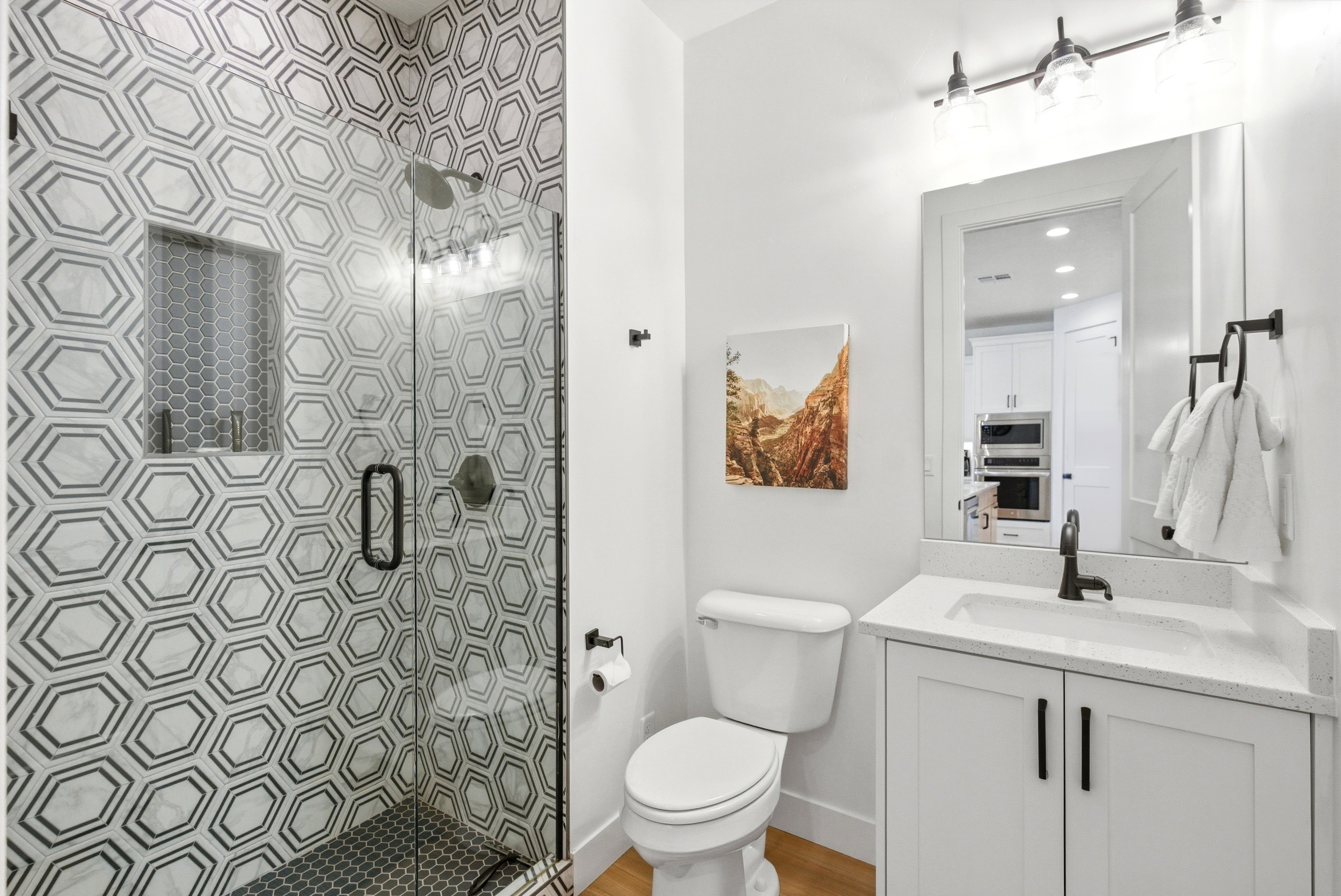 Walk-in shower featuring geometric hexagon wall tiling, a built-in shower niche, and a clear glass enclosure