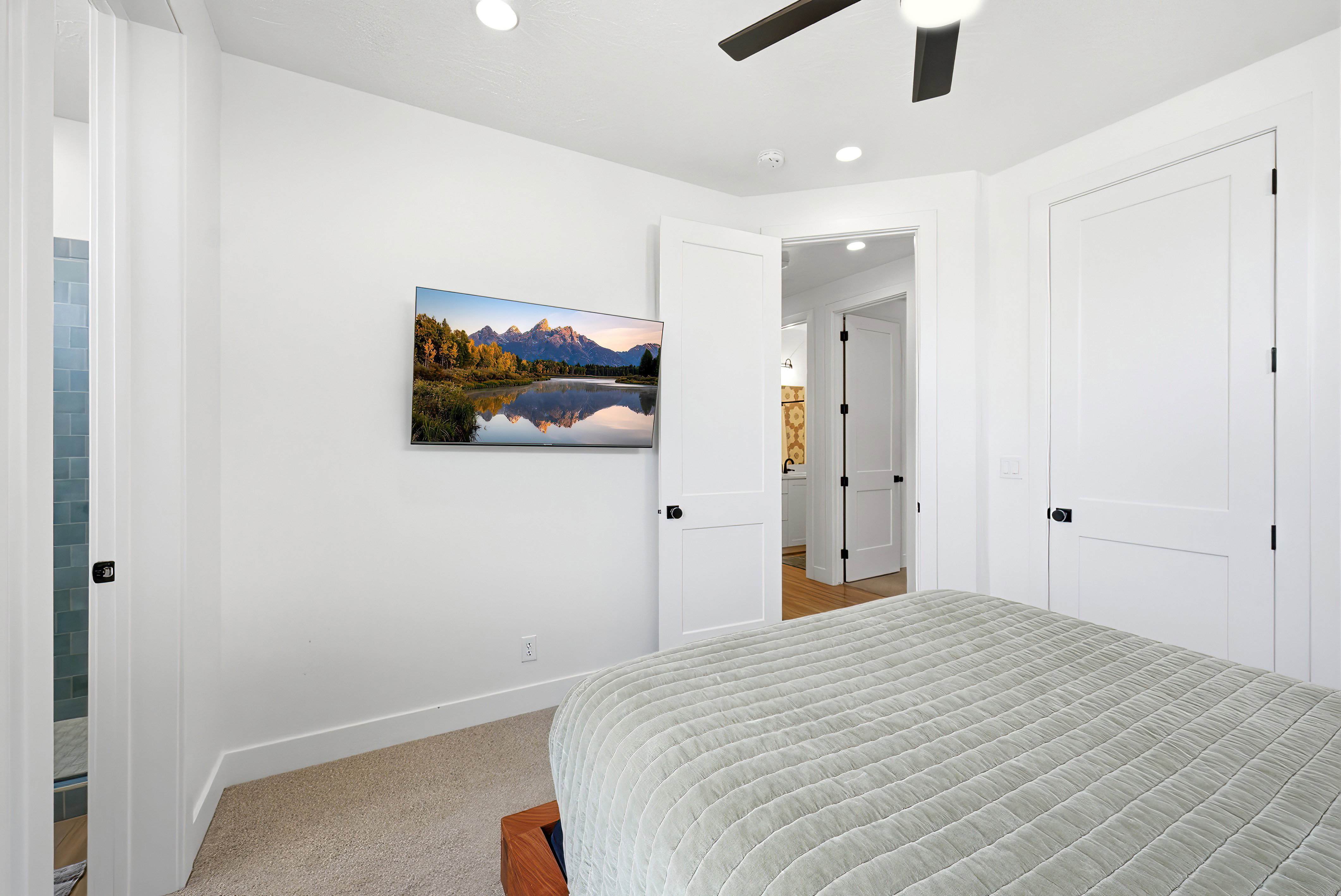Carpeted room with a wall-mounted television, recessed lighting, and a ceiling fan