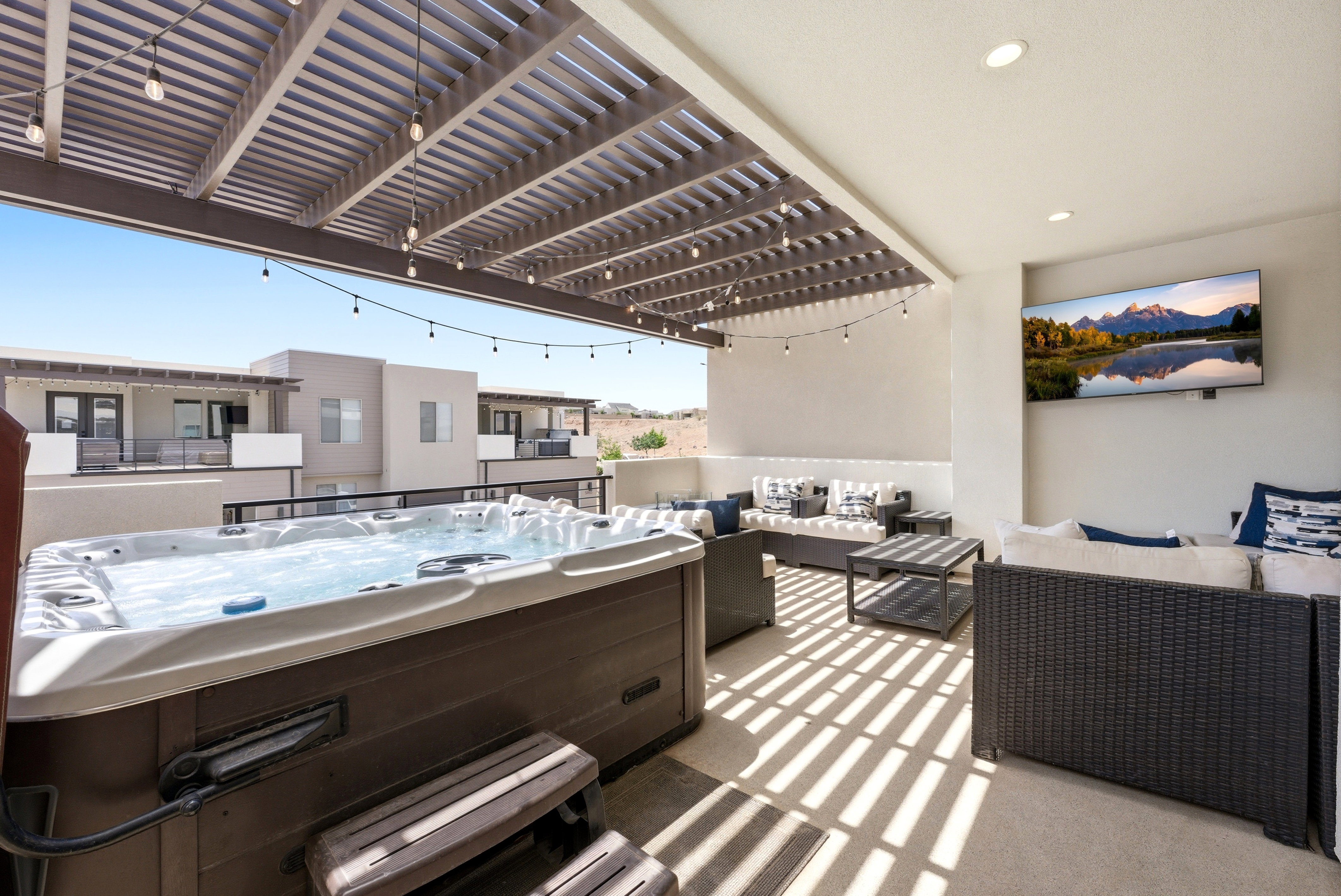 Rooftop patio with an integrated hot tub, slatted pergola, recessed lighting, and a wall-mounted television