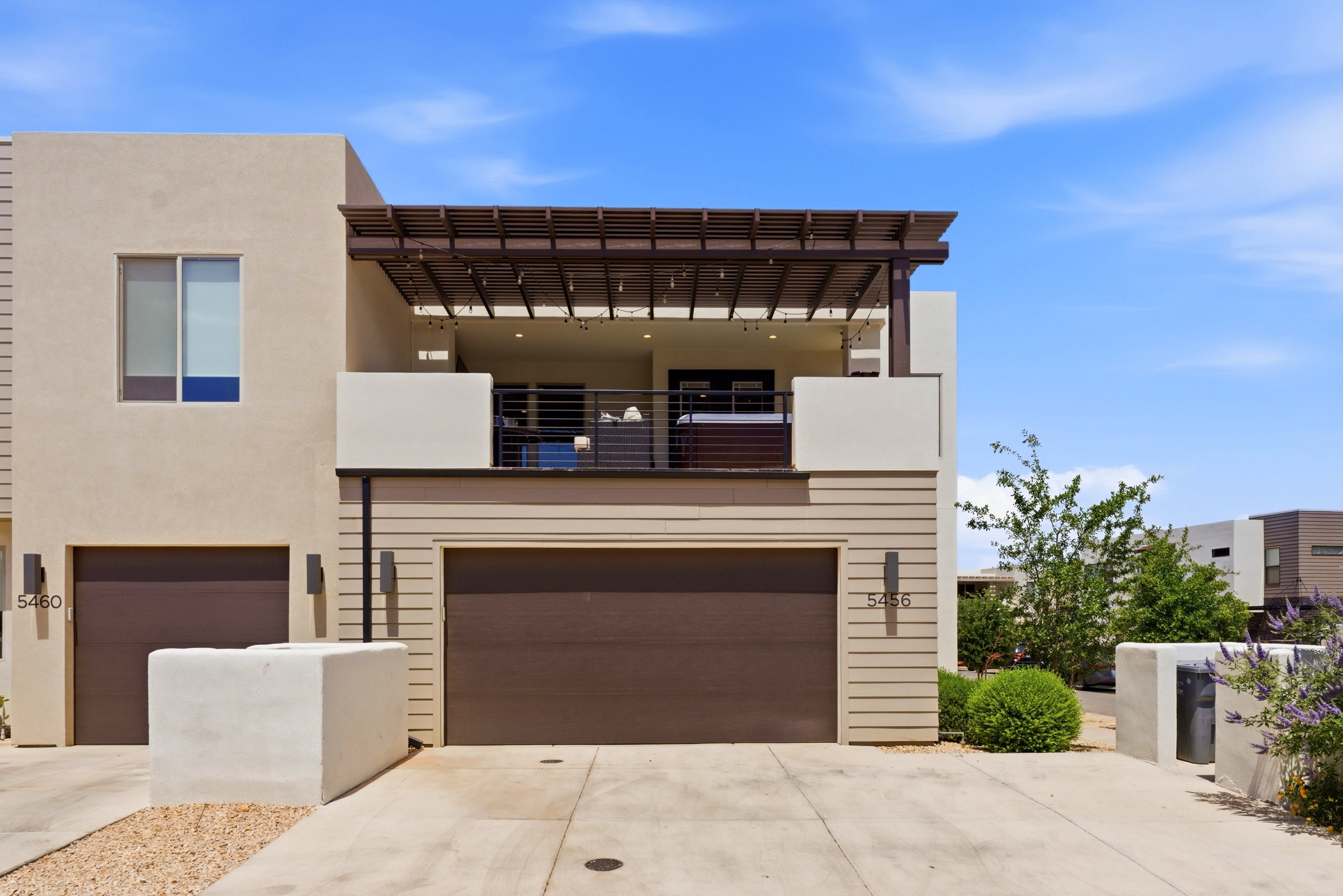 Contemporary exterior with stucco and horizontal siding accents, featuring two attached garages with dark wood-finish doors