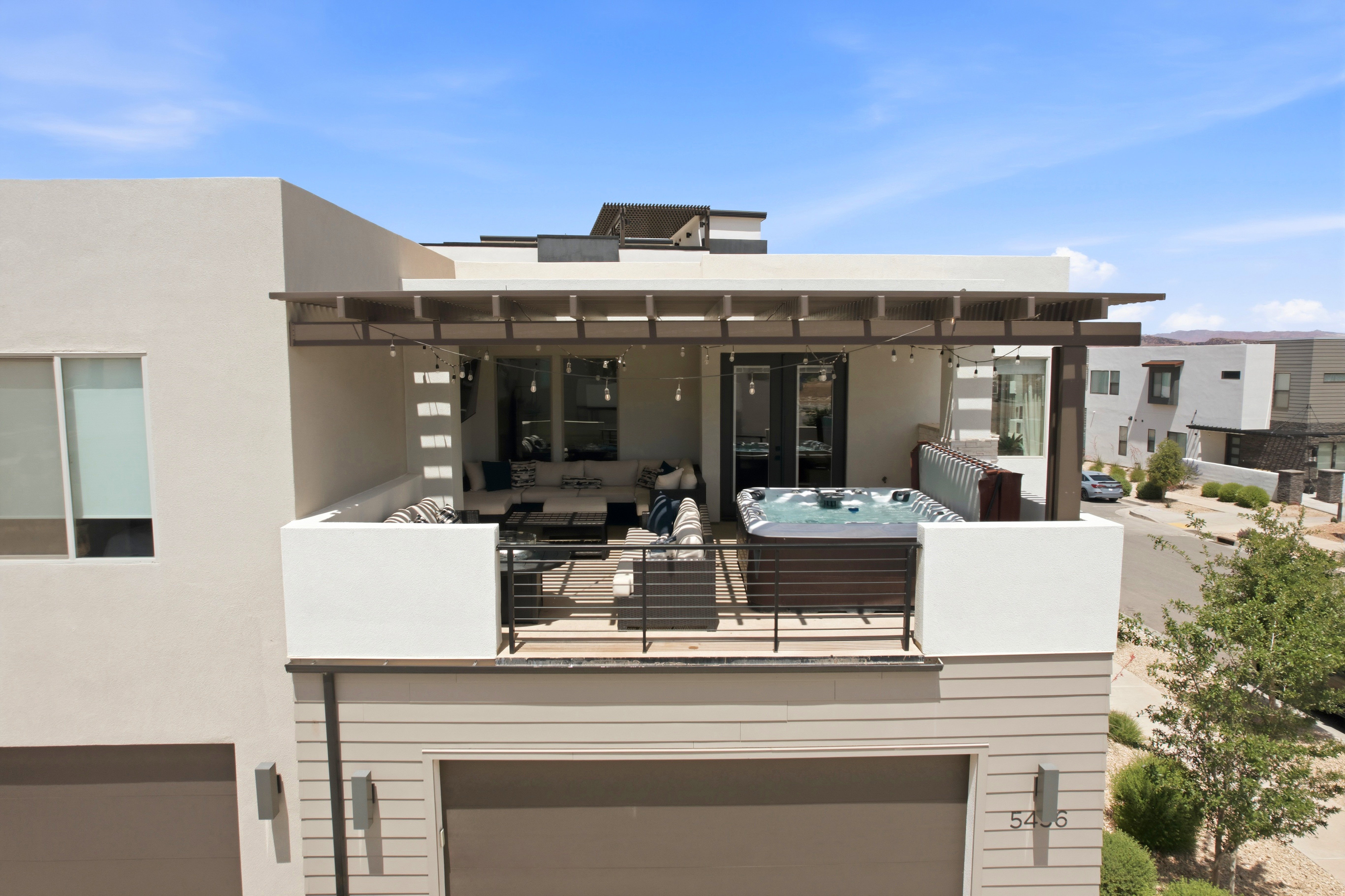 Upper-level balcony featuring a built-in spa, pergola, and modern black railings