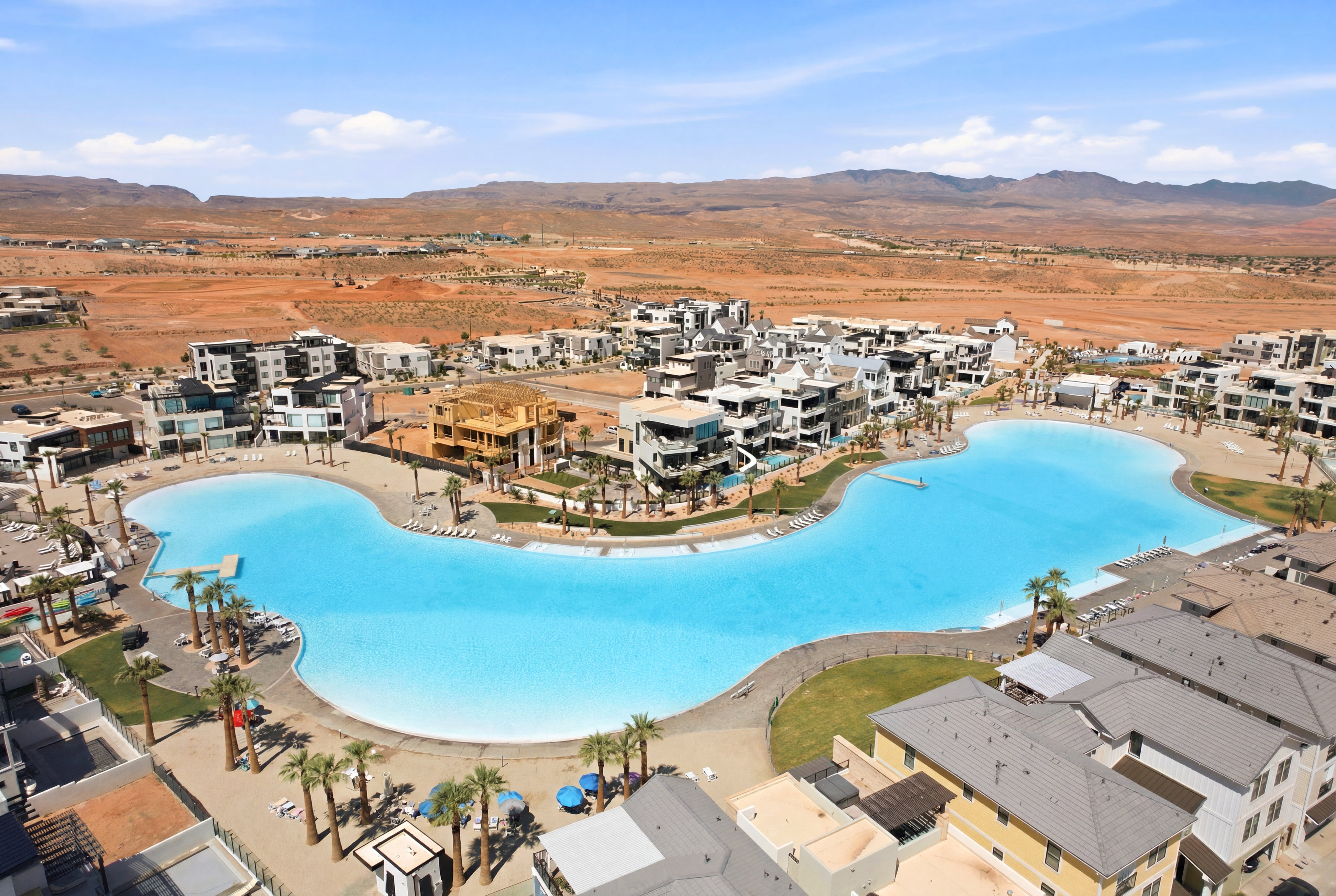 Expansive artificial lagoon with sandy shores and surrounding contemporary residential buildings