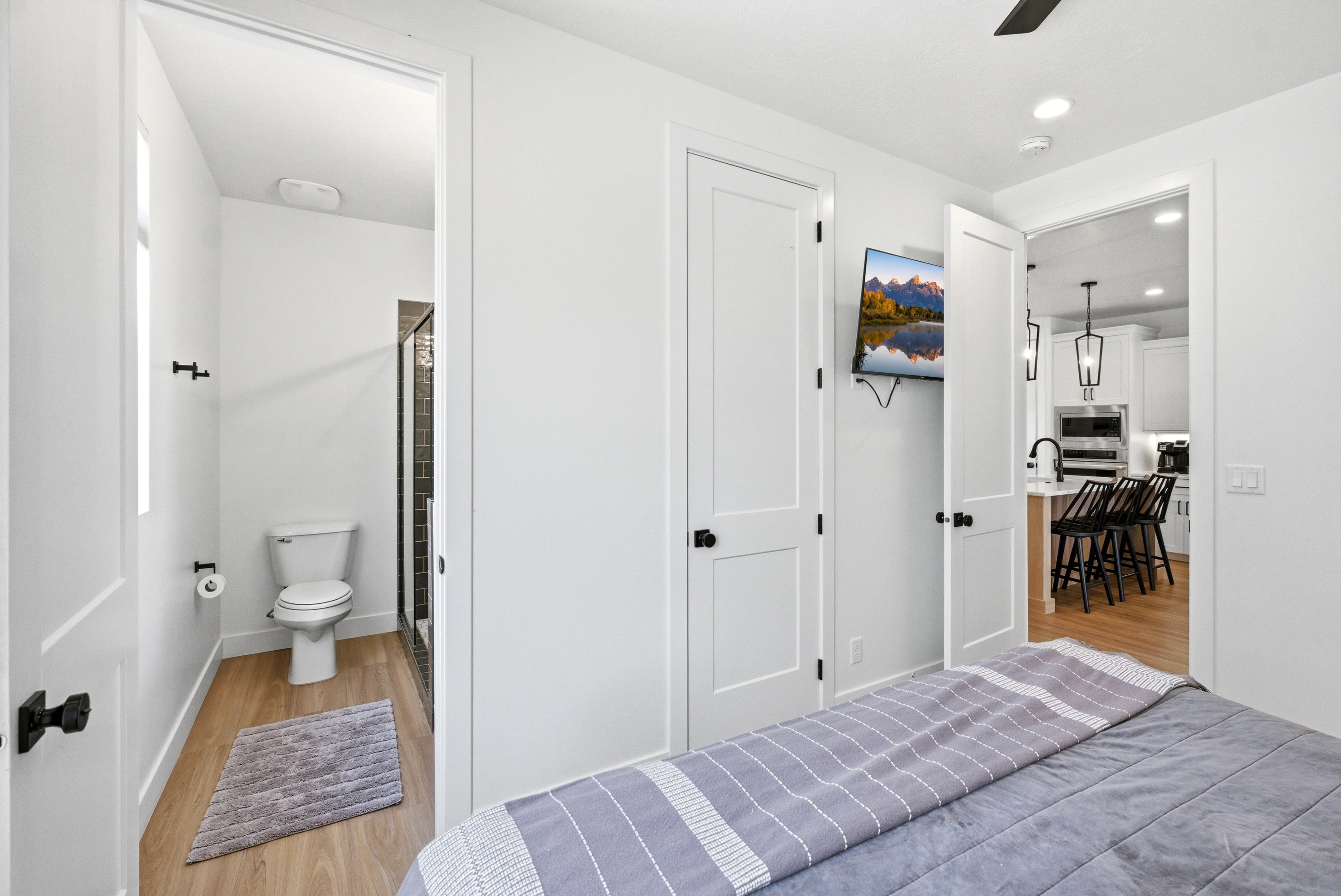 White paneled doors with black hardware, recessed lighting, and wood-finish flooring