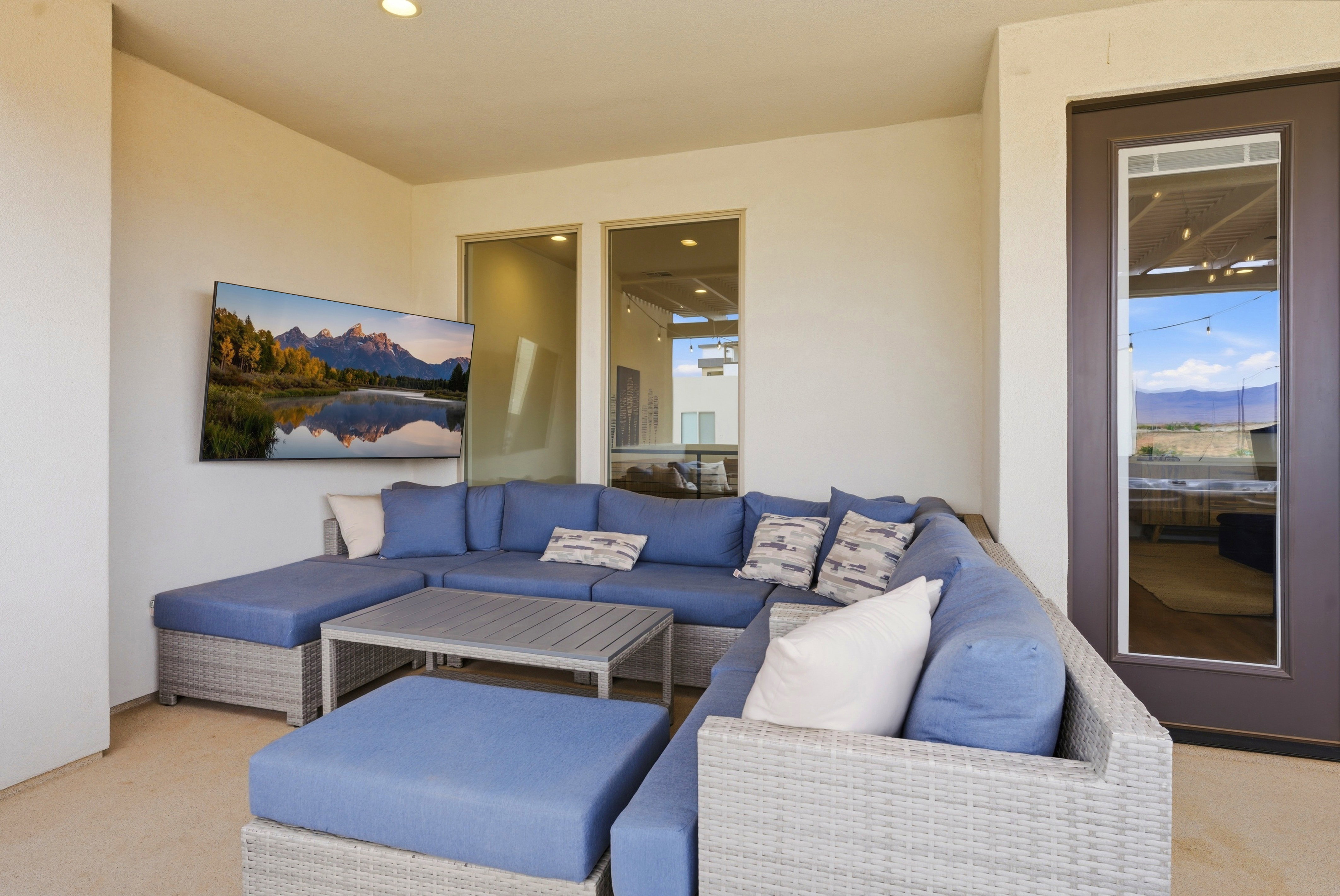 Covered patio space featuring a ceiling-mounted light fixture, a wall-mounted television, and glass panel doors