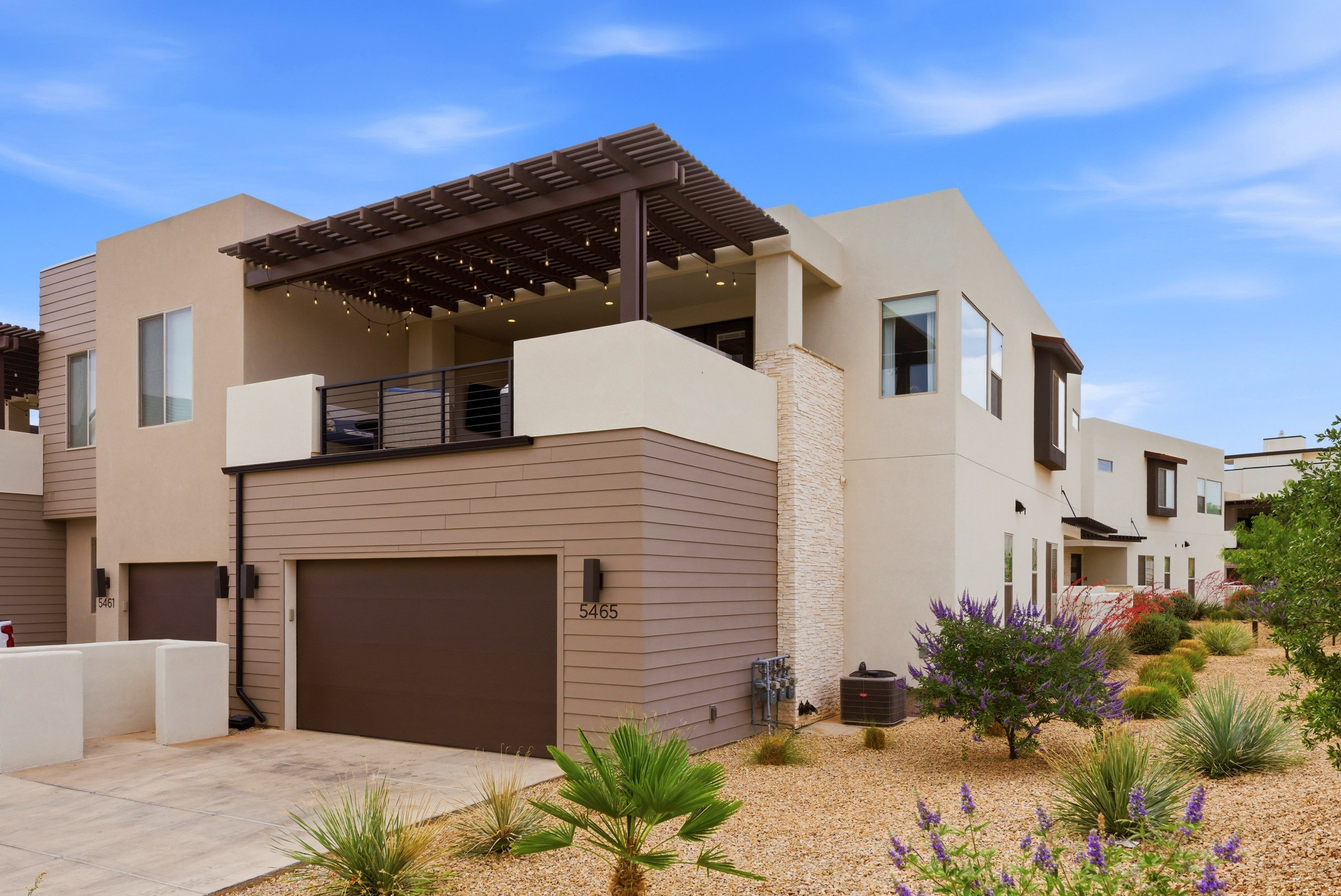 Modern stucco exterior with horizontal siding accents and a stone veneer column