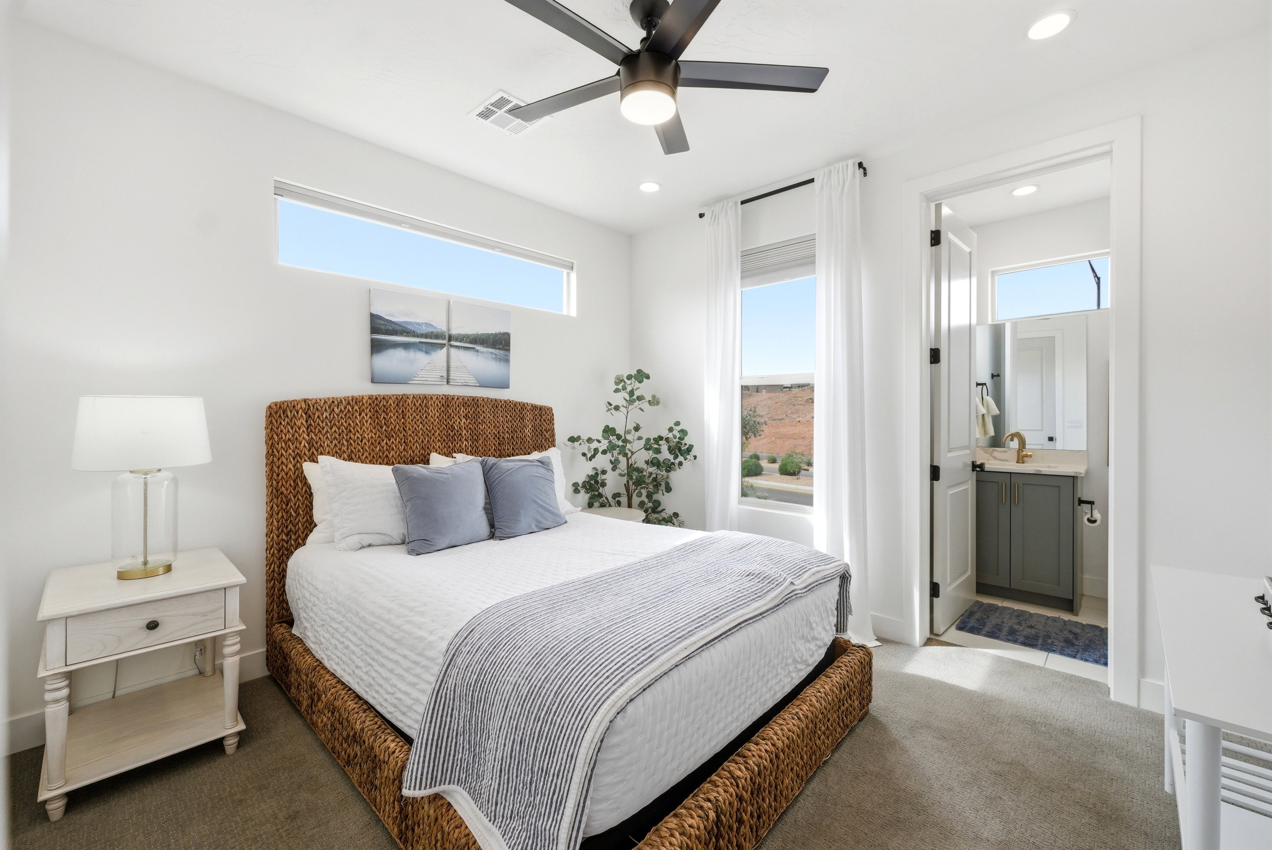 Carpeted bedroom featuring a transom window and a full-height window with white drapes