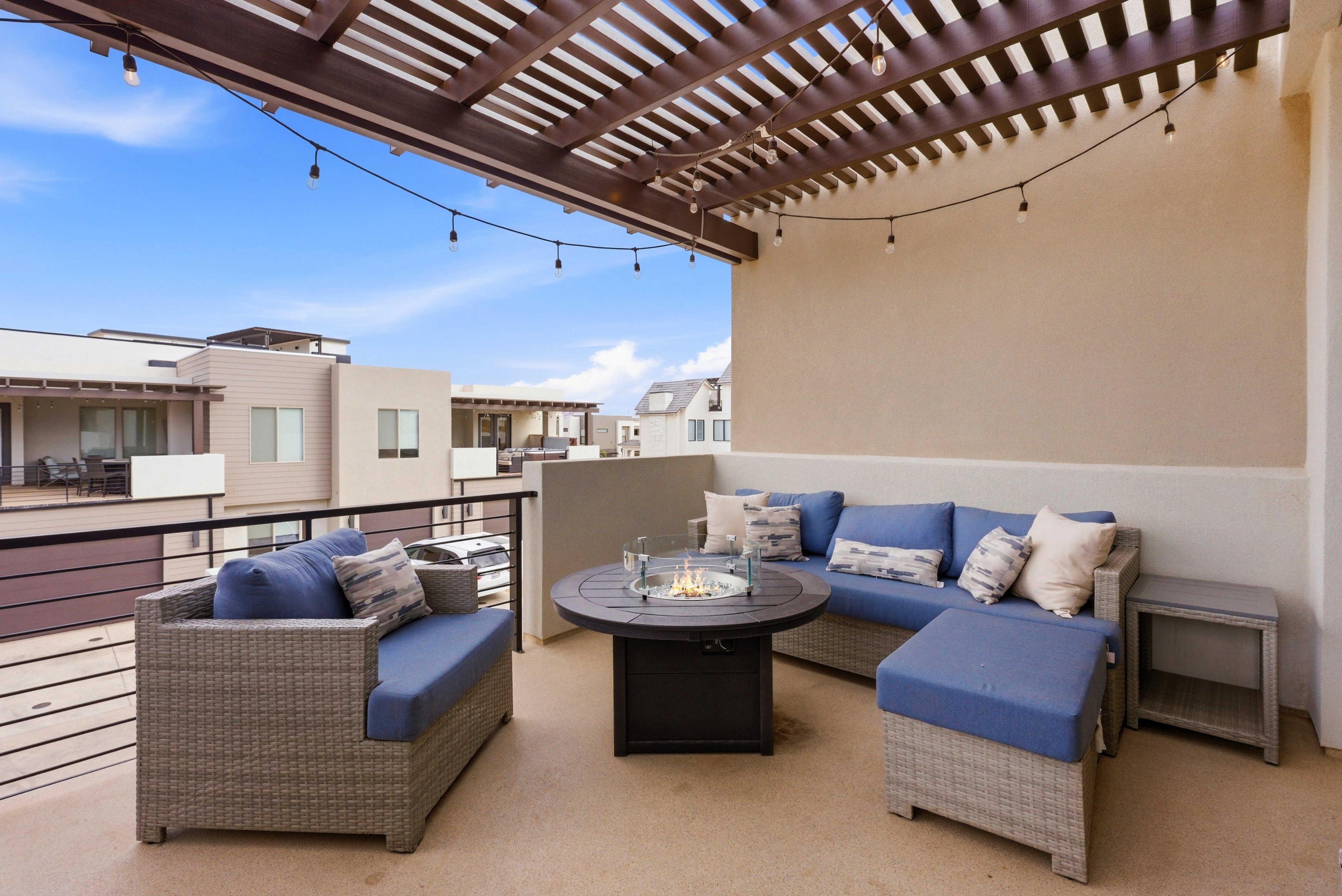Expansive rooftop patio featuring a wood pergola and string lighting