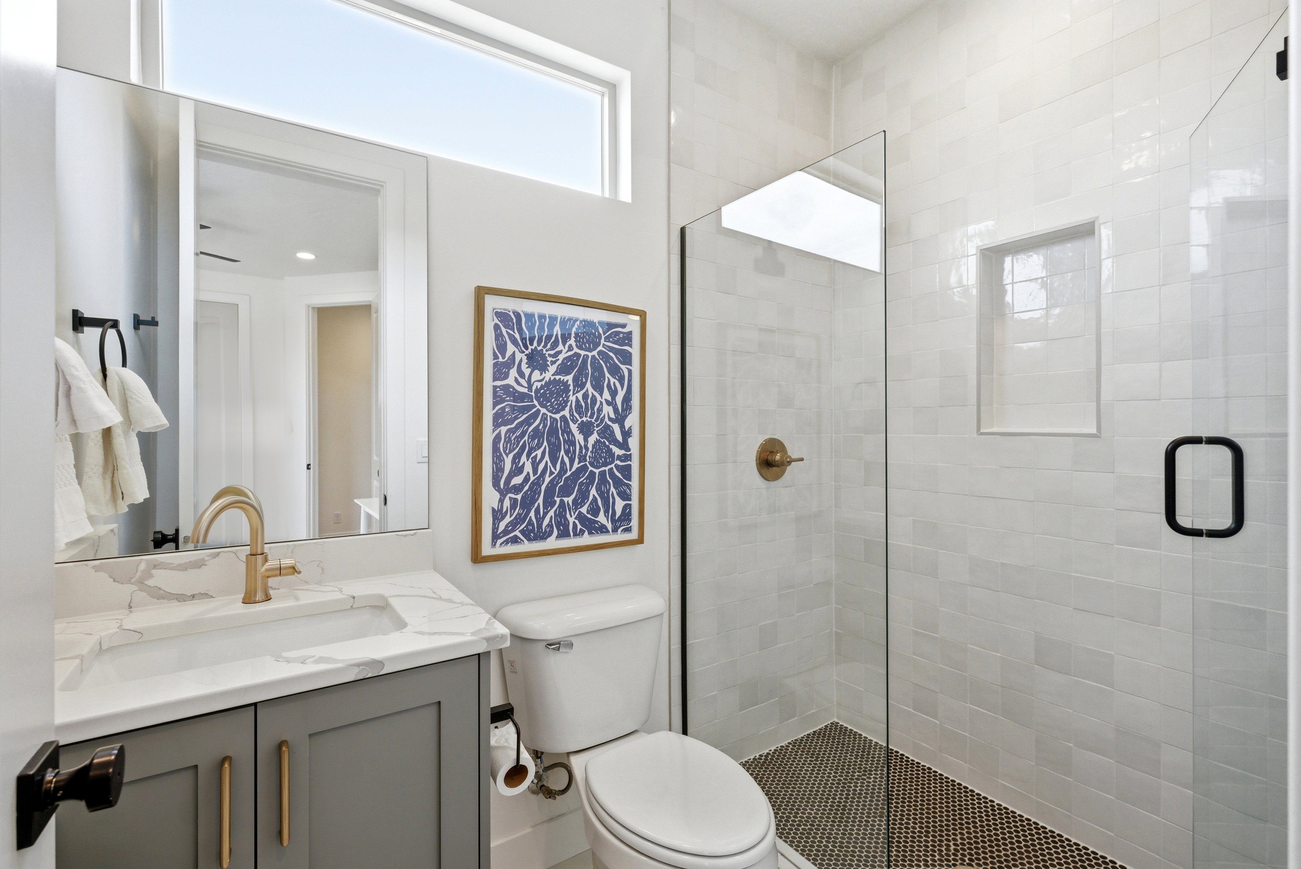 Bathroom featuring a walk-in shower with glass enclosure, white subway tile surround, and black penny tile flooring