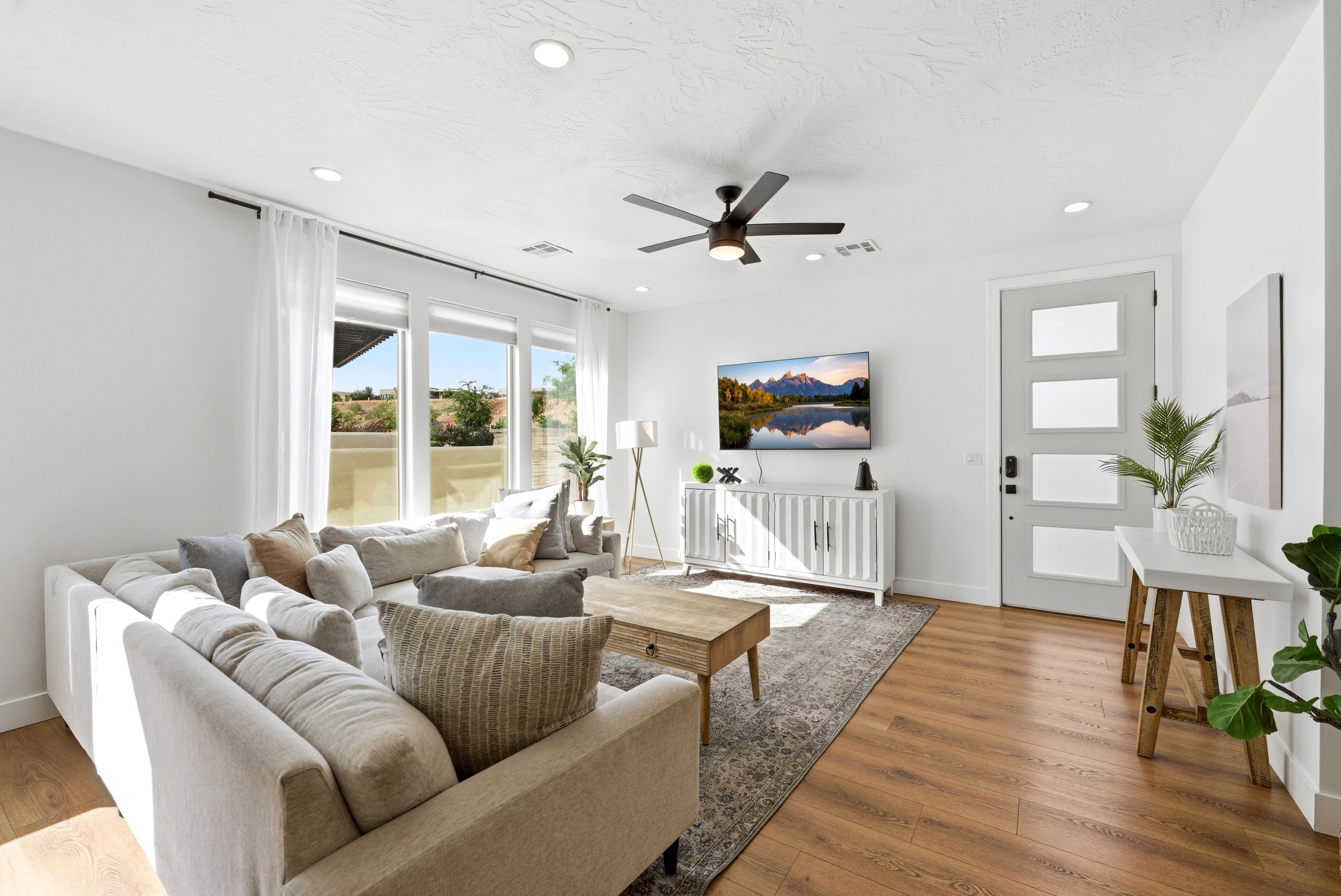 Spacious living area featuring expansive windows, wood-finish flooring, recessed lighting, and a ceiling fan
