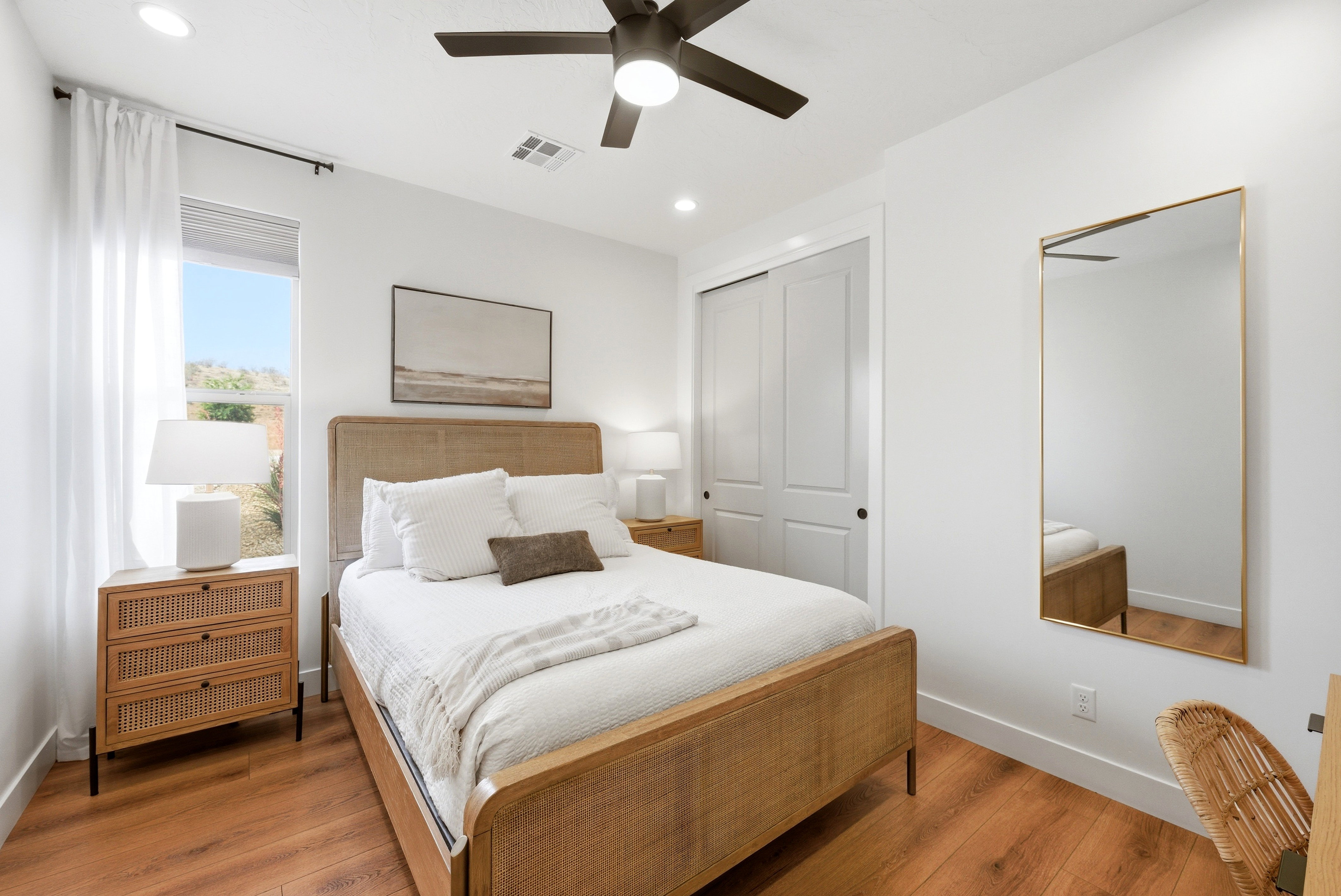 White-painted bedroom featuring wood-finish flooring, a ceiling fan with integrated lighting, and recessed ceiling lights