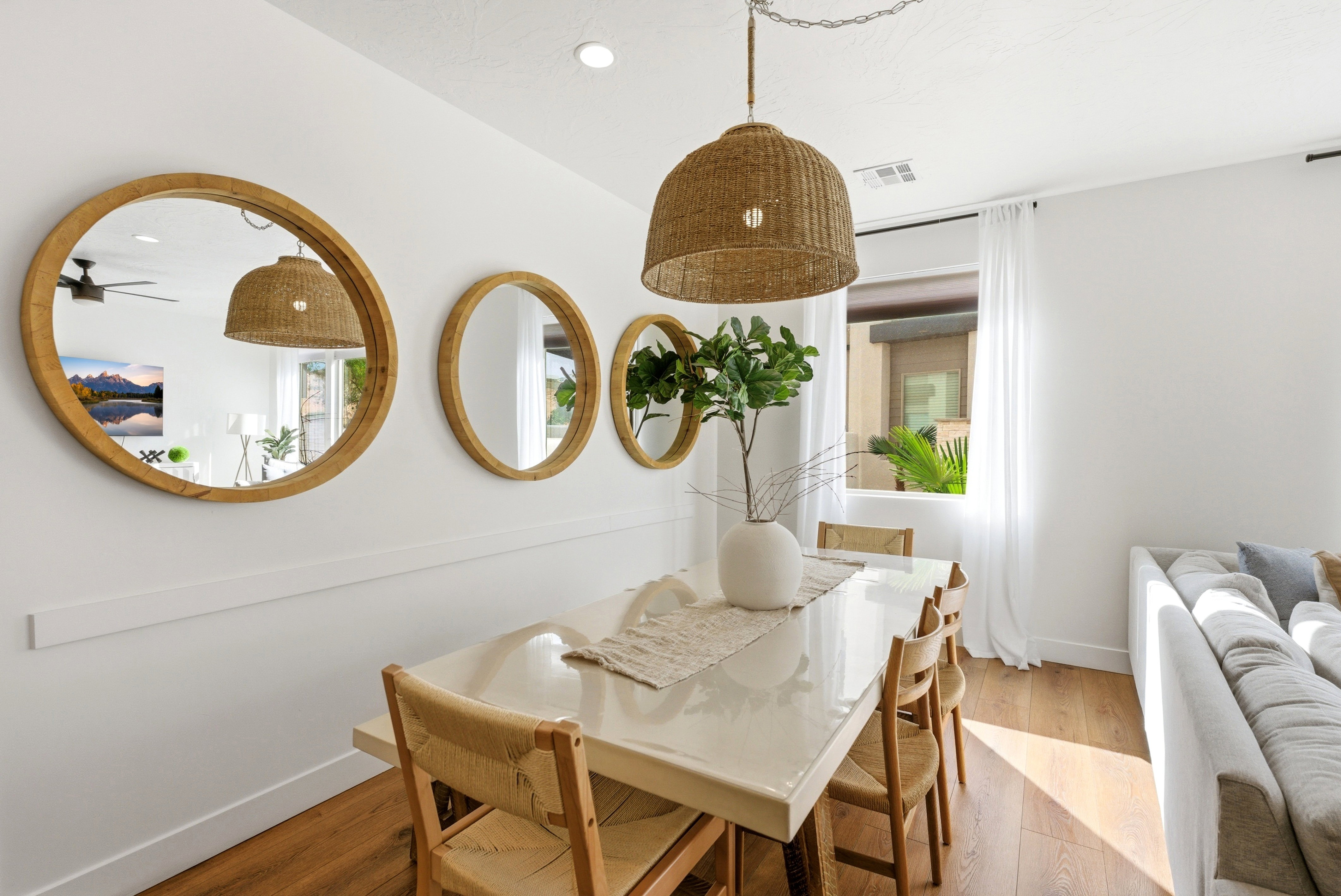 Dining area featuring a contemporary woven pendant light fixture, wood-finish flooring, and a window with sheer white curtains