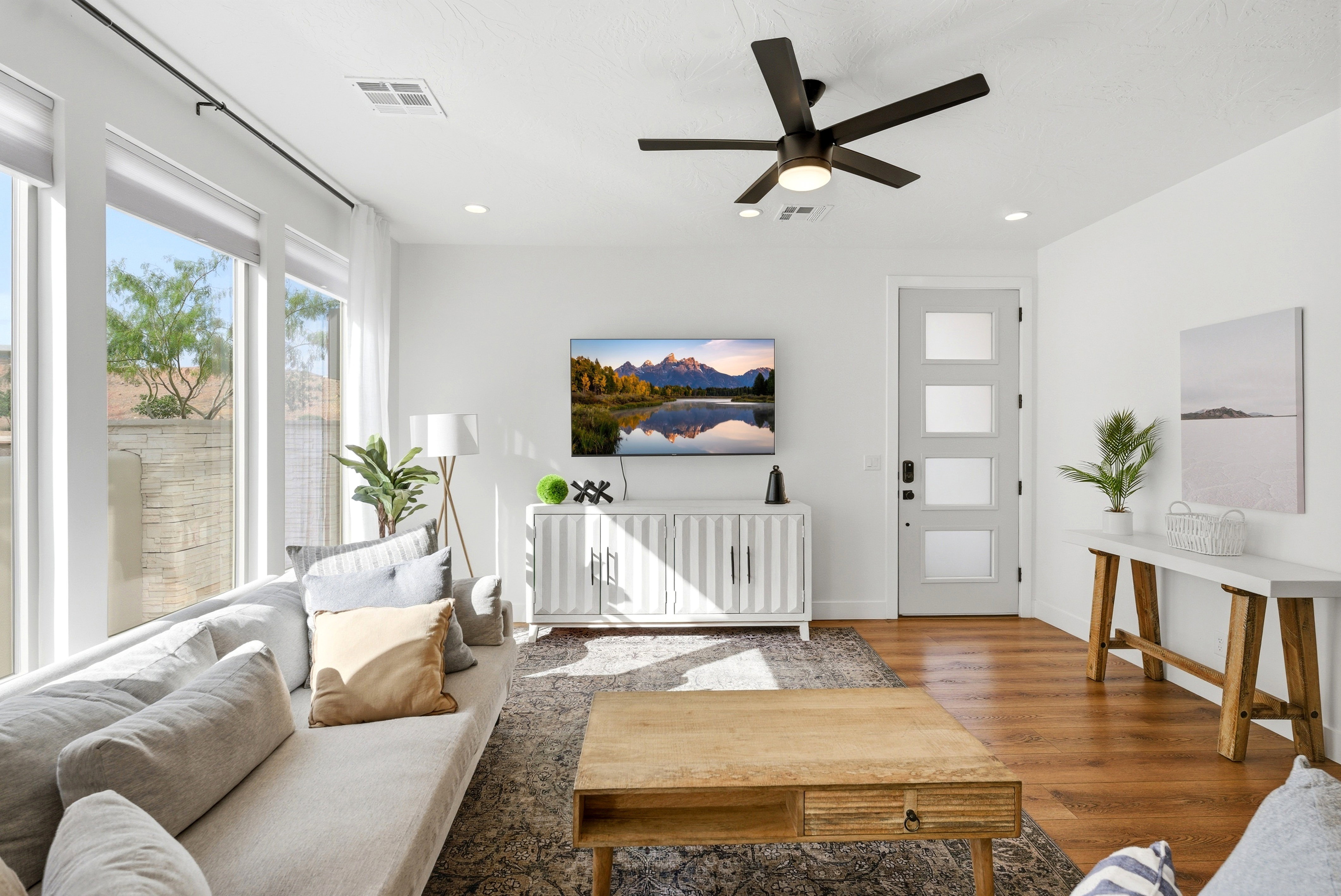 Spacious living area featuring large windows, wood-finish flooring, recessed lighting, and a modern ceiling fan