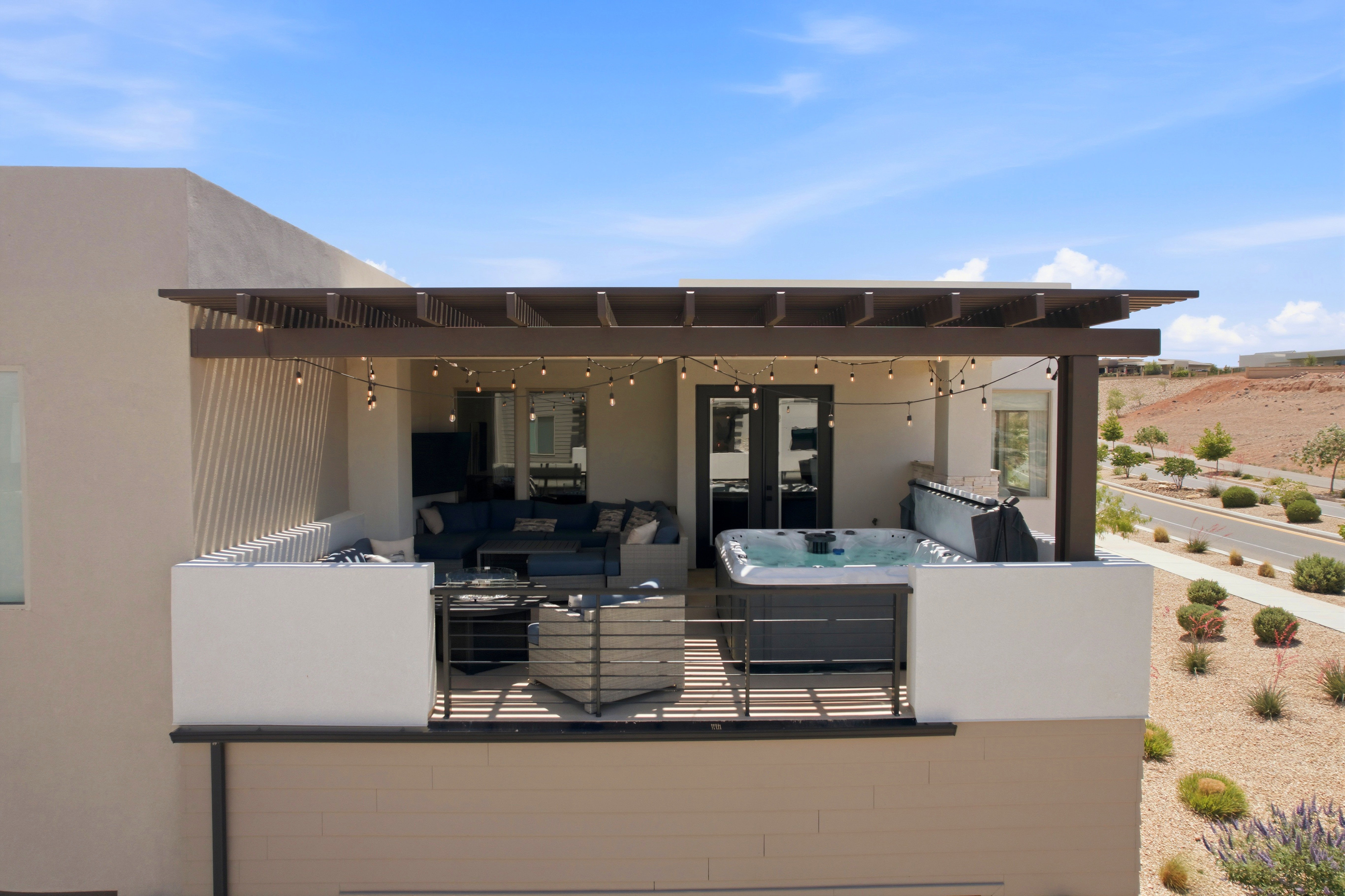 Rooftop patio with a louvered pergola featuring string lighting