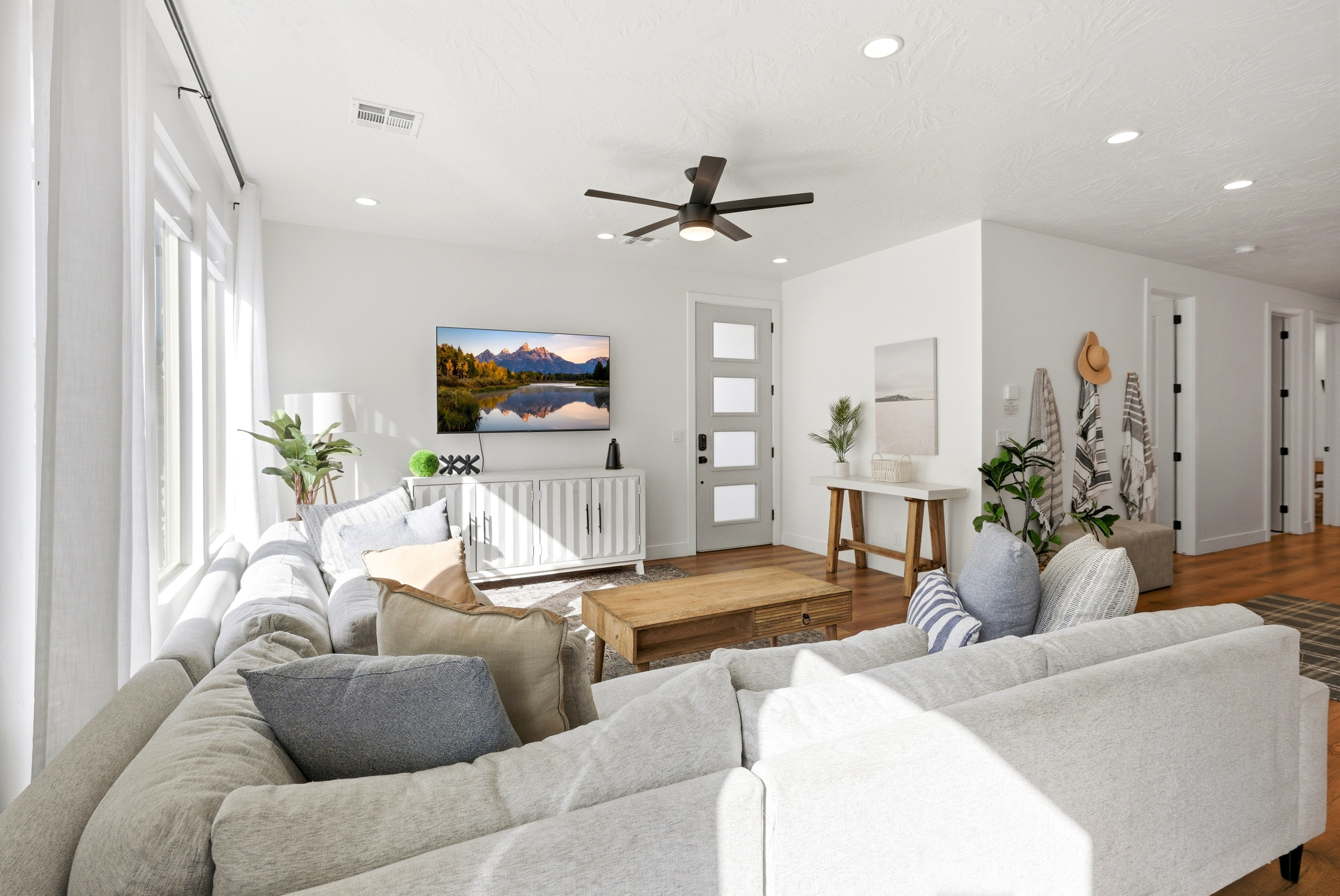 Spacious living area featuring large windows, recessed lighting, wood-finish flooring, a contemporary ceiling fan, and a four-panel frosted glass entry door
